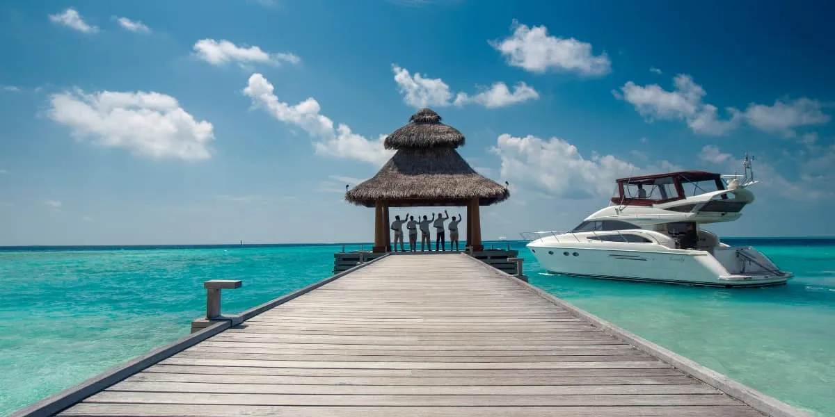 Wooden jetty leading to a thatched pavilion with a motor yacht moored alongside