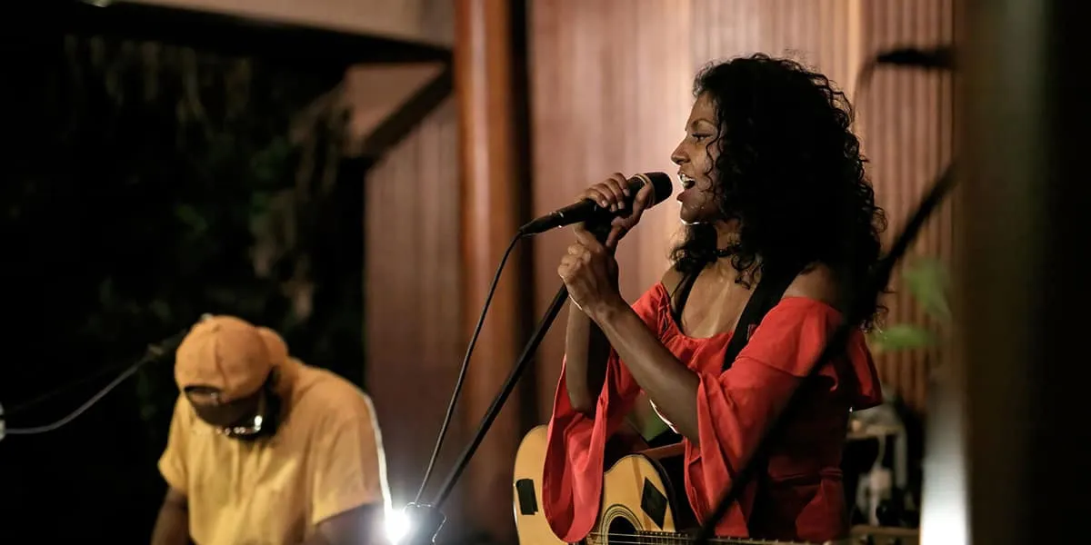 Singer performing with a microphone beside a guitarist at night