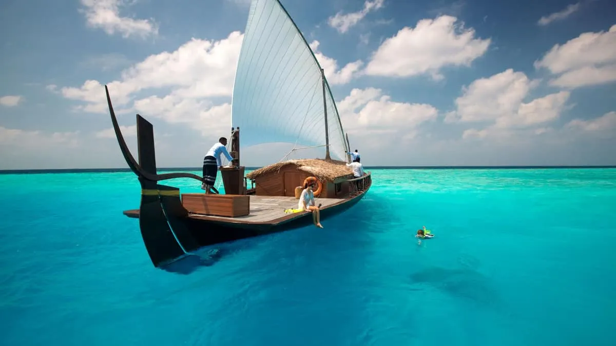 Guests aboard a traditional sailing dhoni on a turquoise lagoon