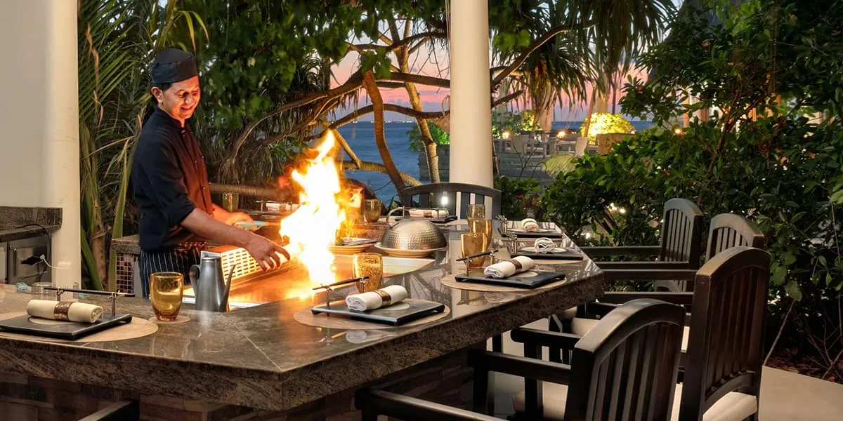 Chef flambéing food at a teppanyaki grill at an outdoor restaurant