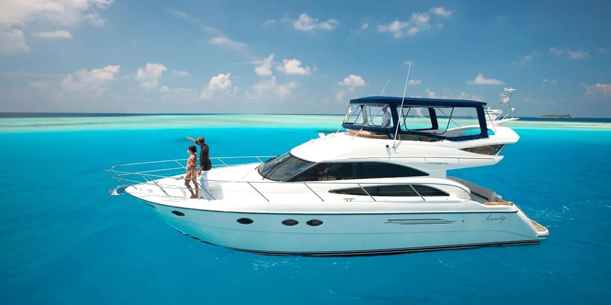 Couple on the bow of a white motor yacht on a turquoise lagoon