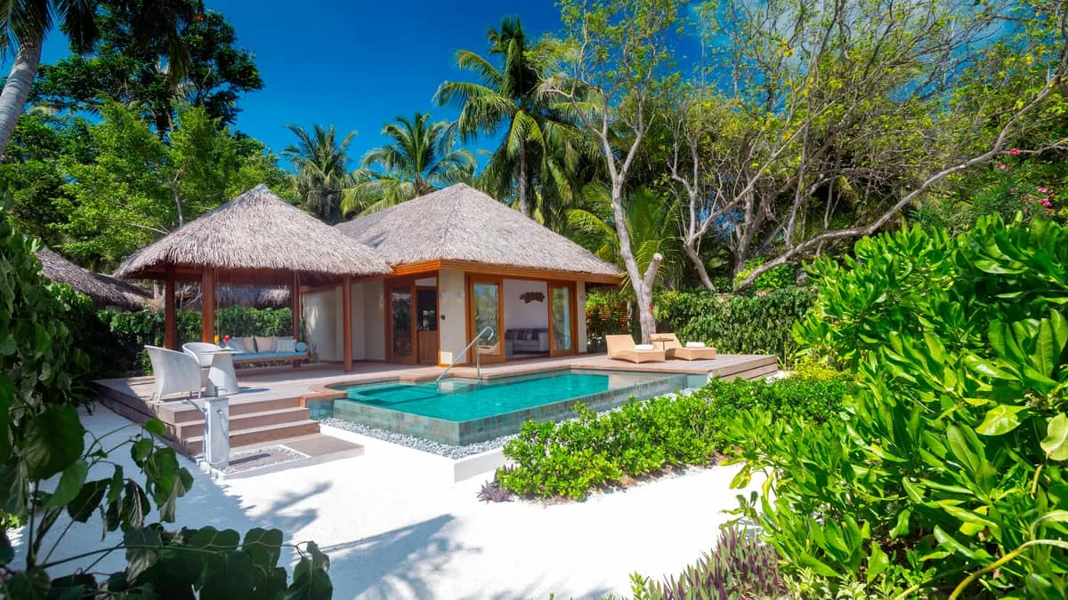 Thatched villa with a private pool and deck surrounded by tropical garden