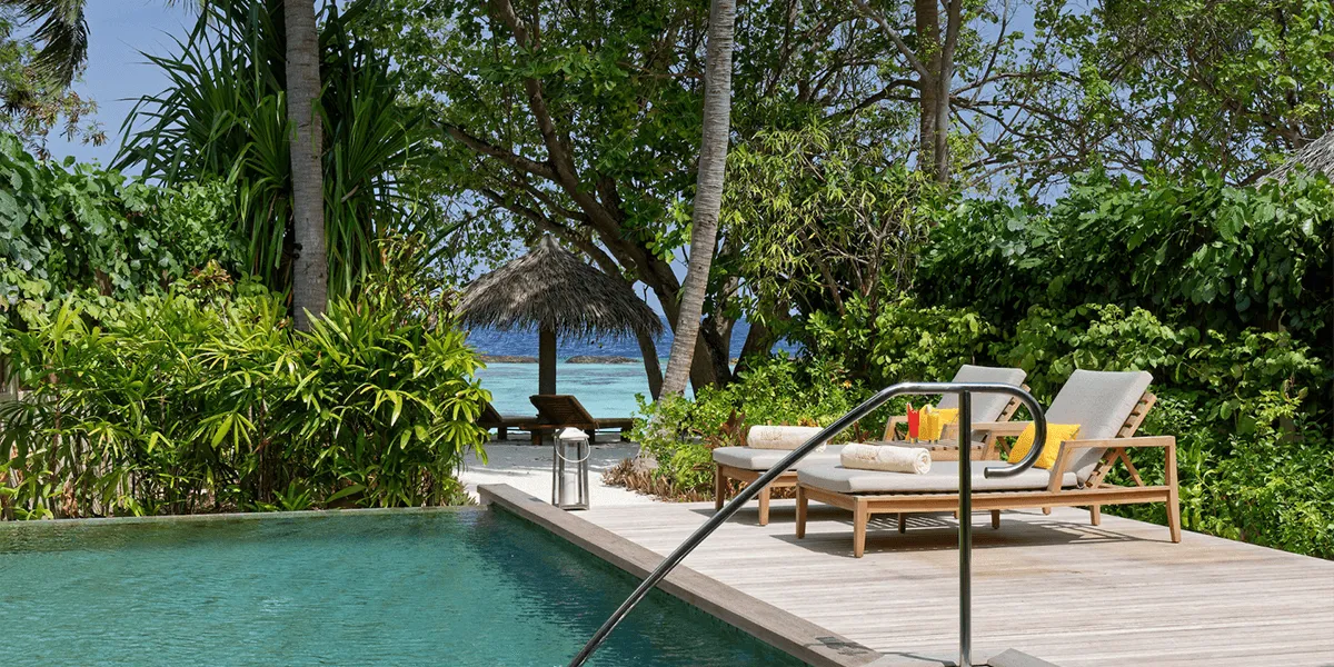 Private pool and sun loungers on a wooden deck surrounded by tropical plants