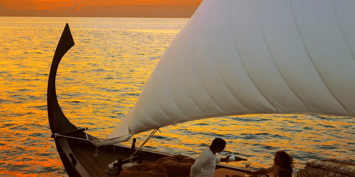 Guests dining aboard a traditional sailing dhoni at sunset