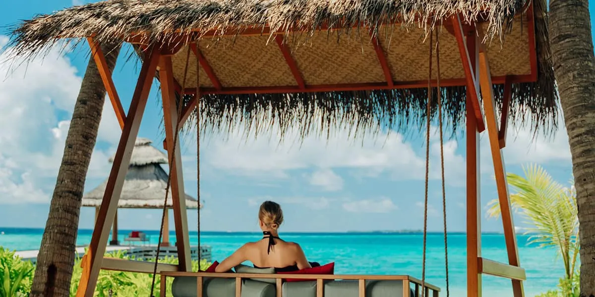 Woman on a thatched swing seat looking out over the sea