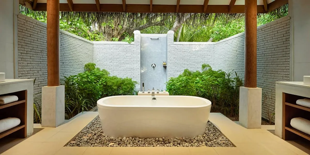 Outdoor bathroom with a freestanding bathtub, rain shower and garden