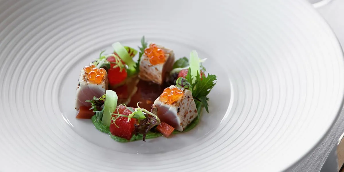 Plated seafood starter garnished with herbs and roe in a white bowl