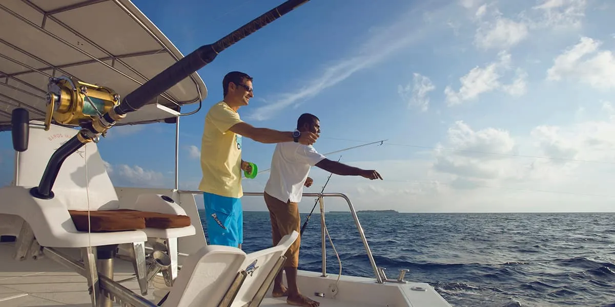 Two men trolling with hand lines from the back of a boat on the open sea