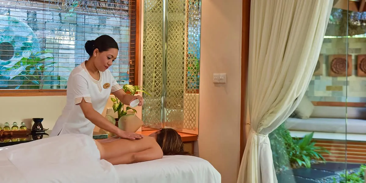 Therapist giving a back massage in a bright spa treatment room