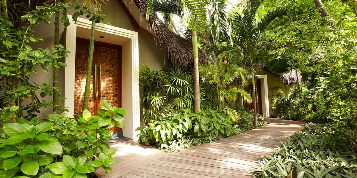 Spa entrance beside a wooden walkway through tropical gardens