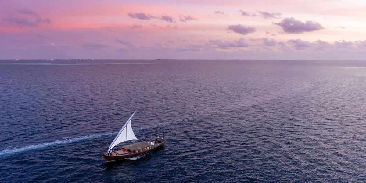 Traditional dhoni sailing across the ocean at dusk