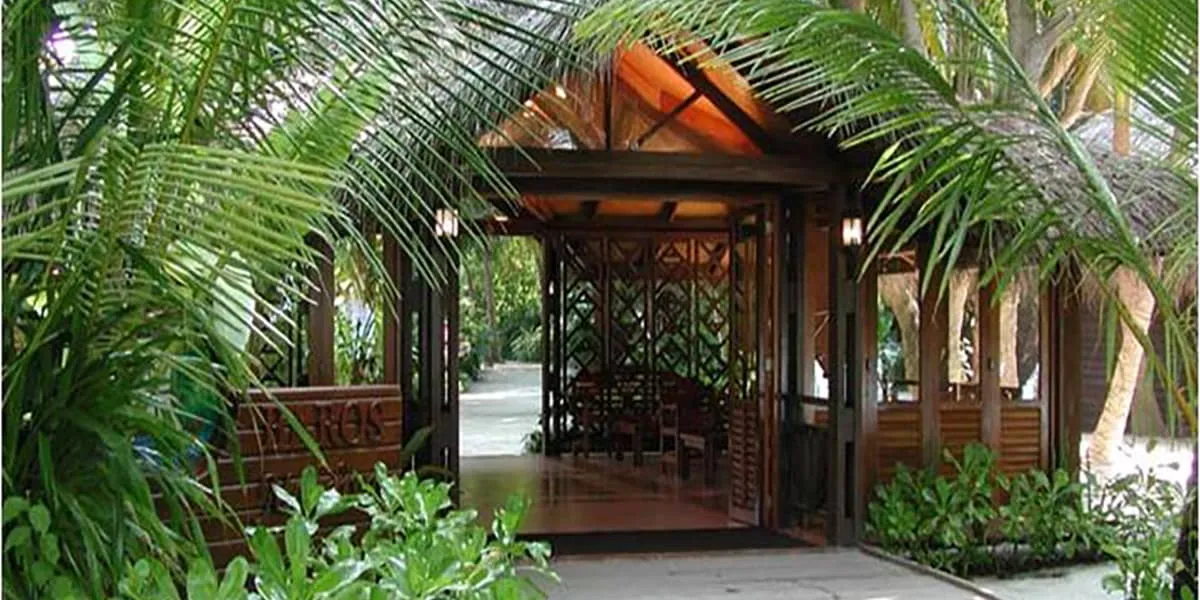 Timber entrance pavilion framed by palms and tropical plants