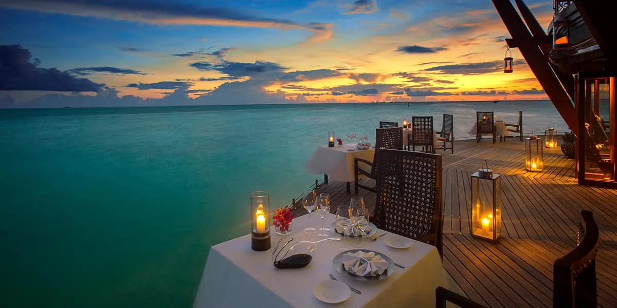 Lantern-lit dining terrace over the lagoon at sunset