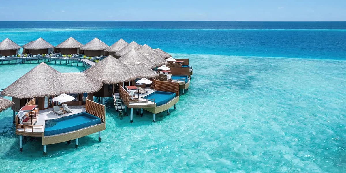 Water villas with thatched roofs and sun decks above a turquoise lagoon