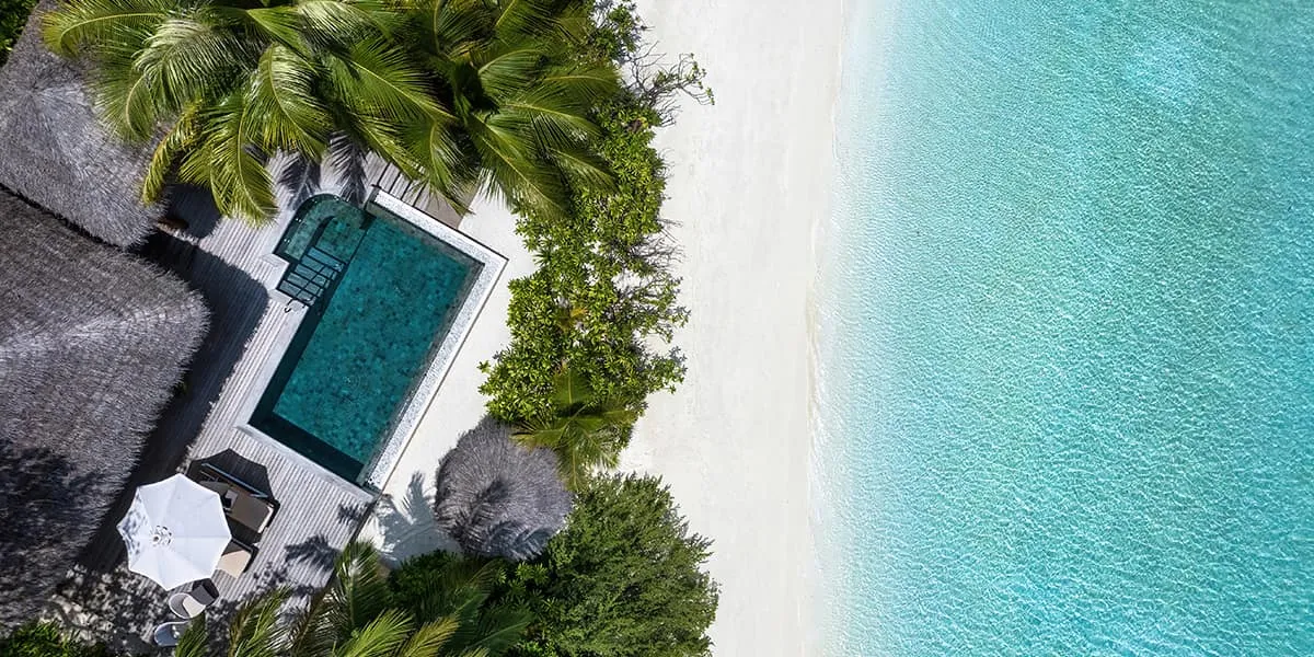 Aerial view of a Baros Suite with a private pool beside a white-sand beach