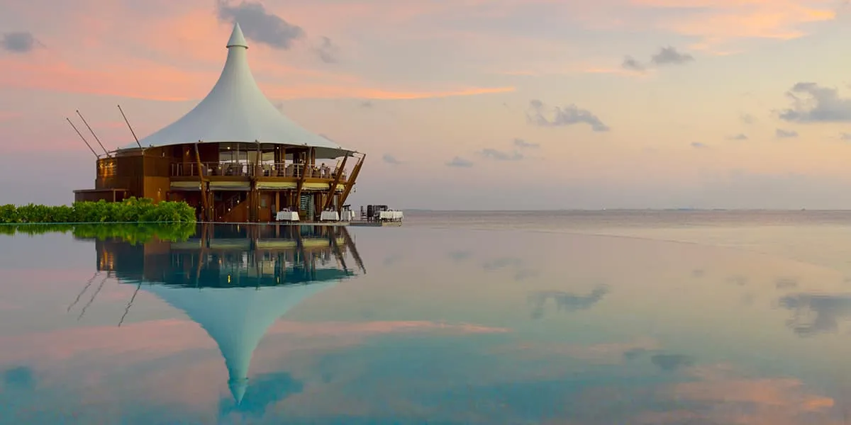 The Lighthouse restaurant reflected in a calm lagoon at sunset