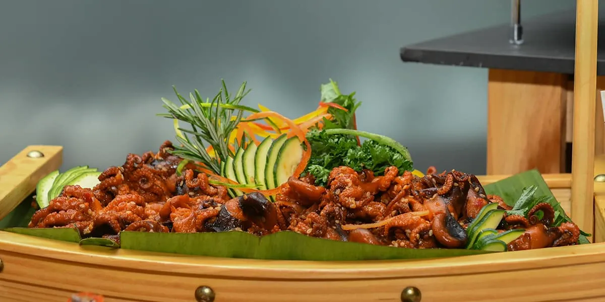 Grilled seafood garnished with vegetables served on a banana leaf