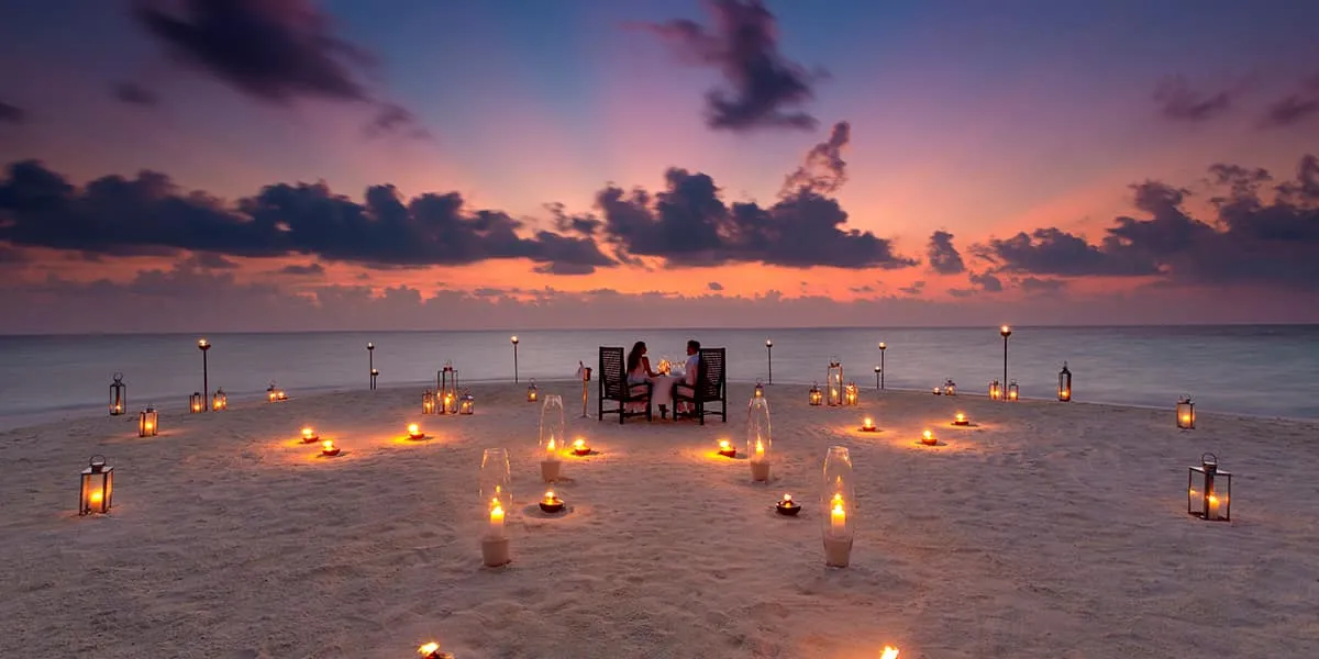 Candlelit dinner for two on a sandbank beneath a dramatic dusk sky