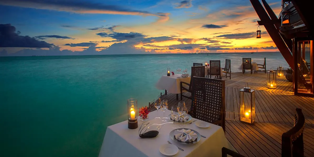 Lantern-lit dining terrace over the lagoon at sunset
