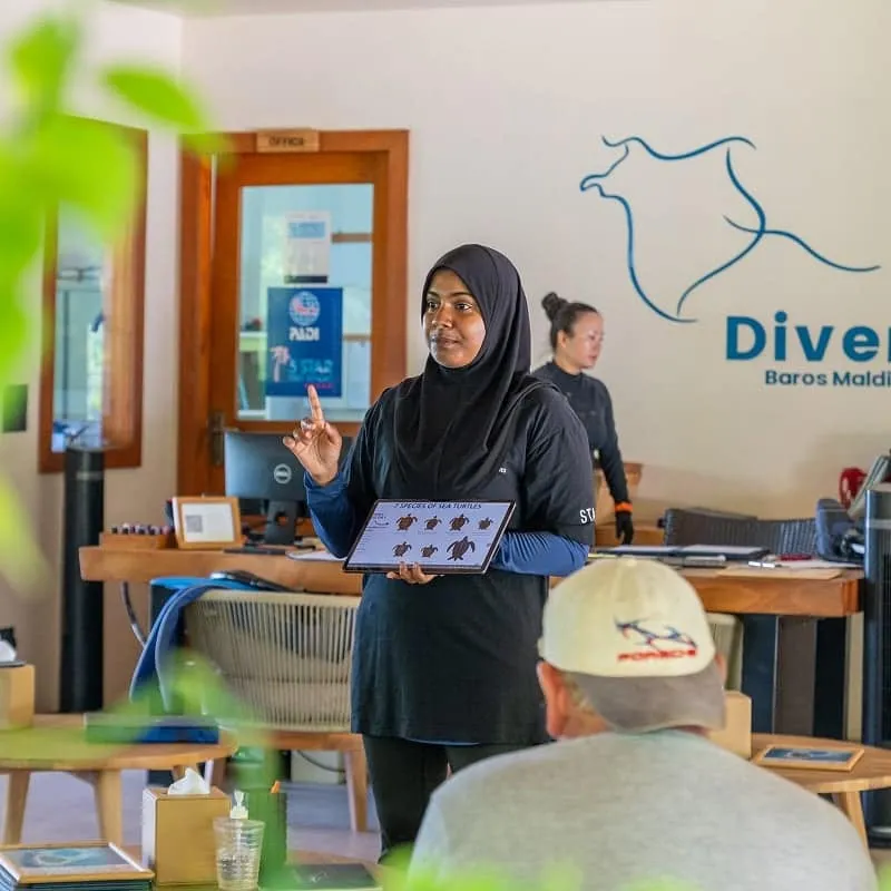 Instructor holding a tablet of sea turtle species at a briefing in the Divers centre