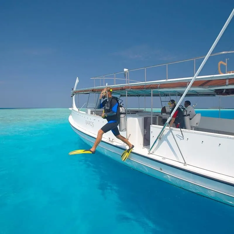 Diver taking a giant stride off a dive boat into turquoise water