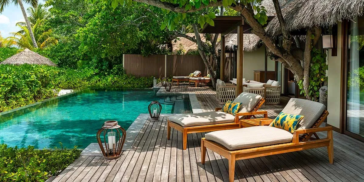 Pool deck with sun loungers and lanterns beside a private villa pool