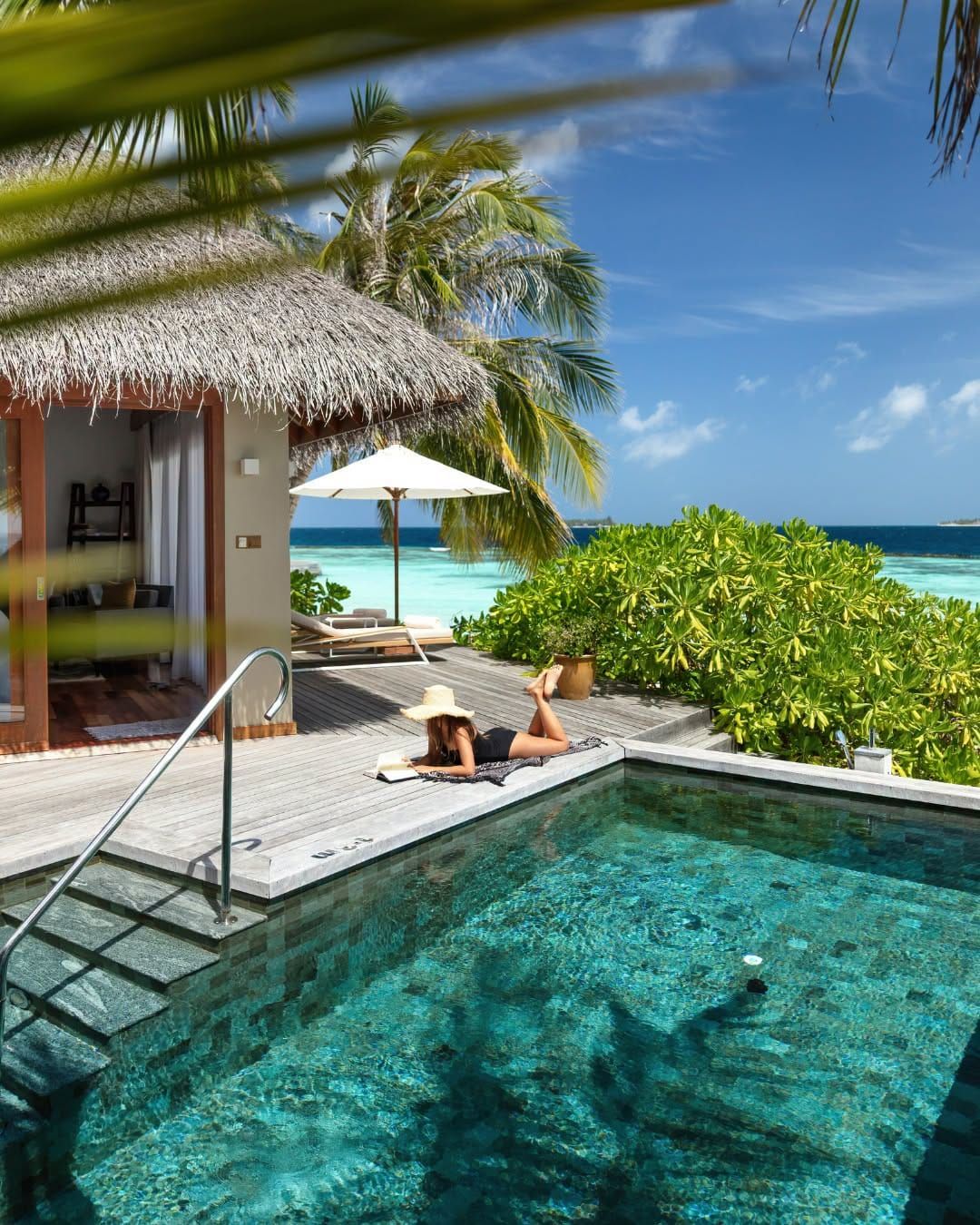 Private plunge pool and sun deck beside a thatched beach villa, with the sea beyond
