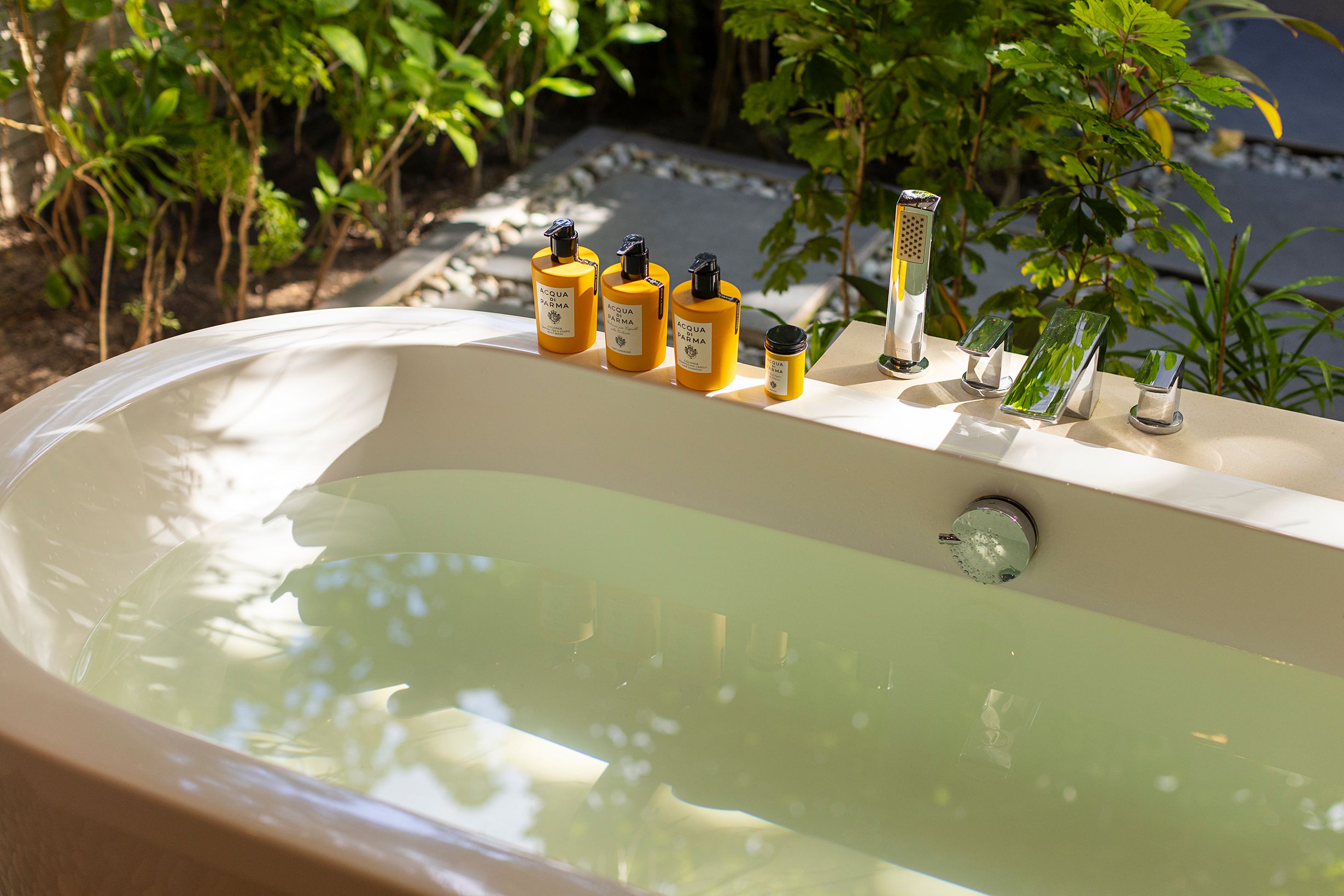 Close-up of a filled bath with bath amenities in a Deluxe Beach Villa garden bathroom
