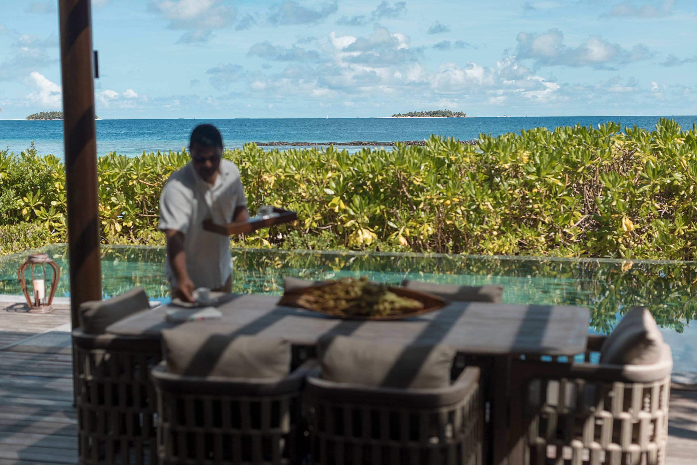 A butler setting the table at a Baros Retreat pool terrace
