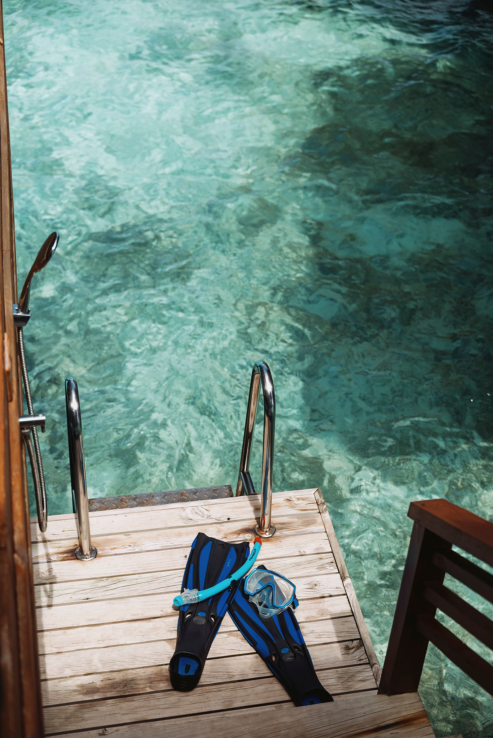 Snorkel fins and mask on a villa deck beside the turquoise lagoon