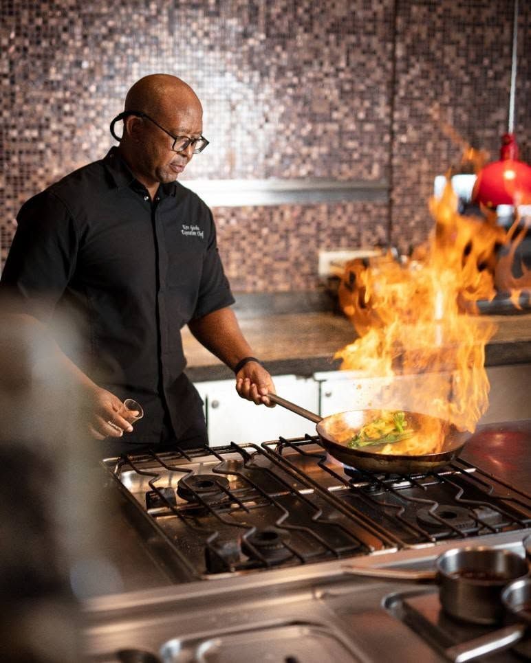 A chef cooking over open flames at Cayenne Grill