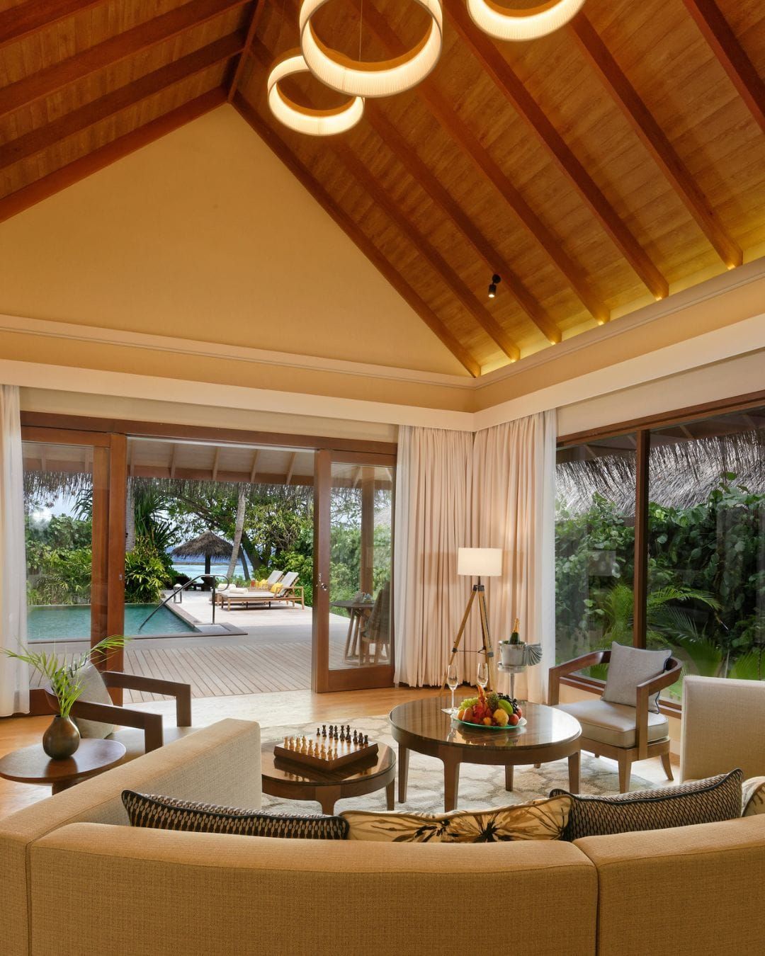 Villa living room with vaulted timber ceiling and sofas facing garden doors