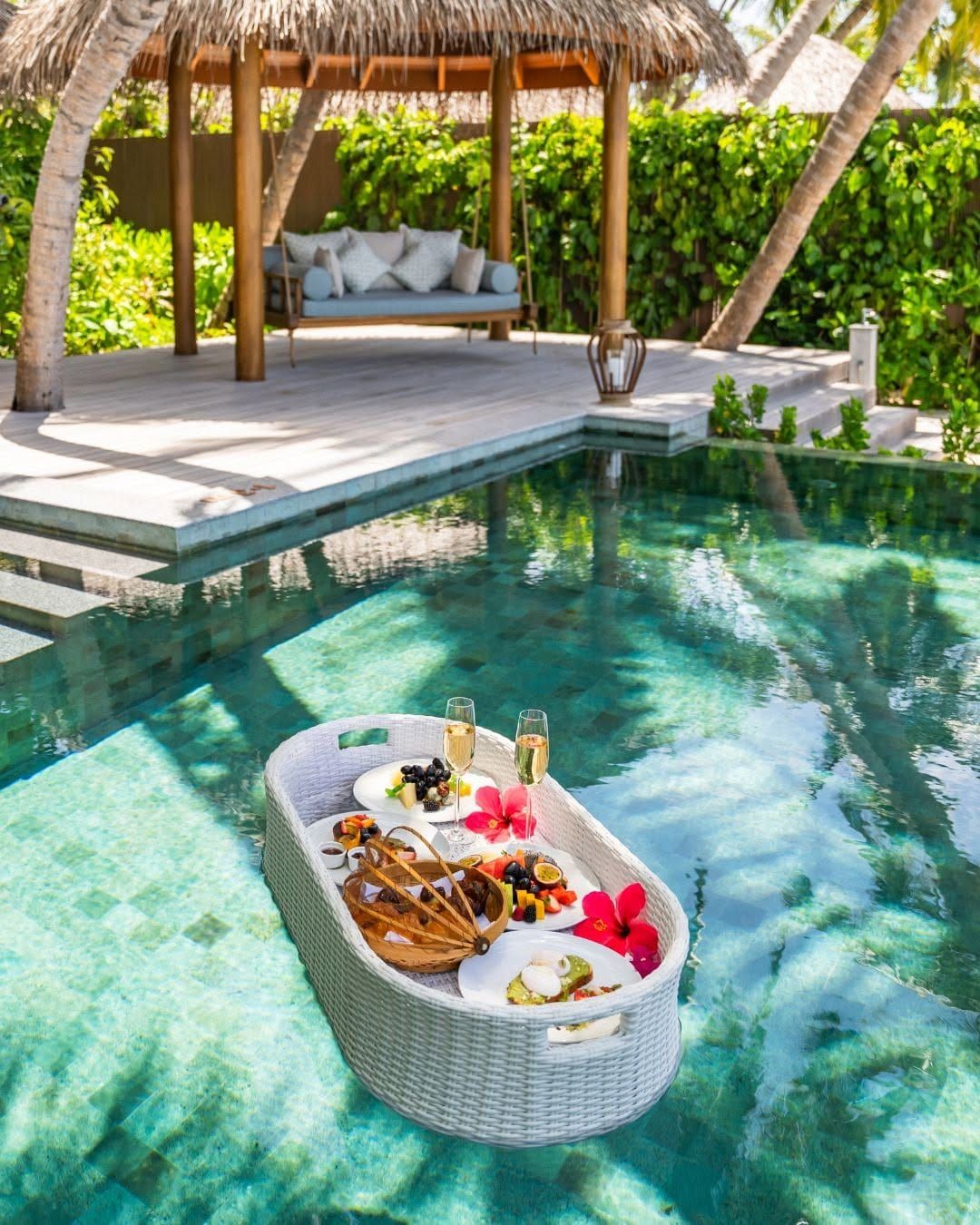Floating breakfast tray in a private villa pool beside a thatched pavilion