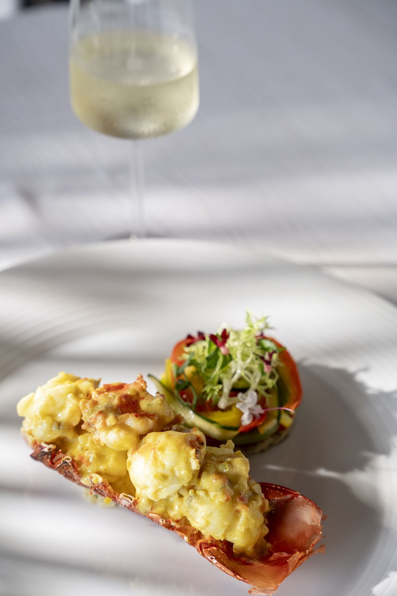 A plated dish with a glass of white wine