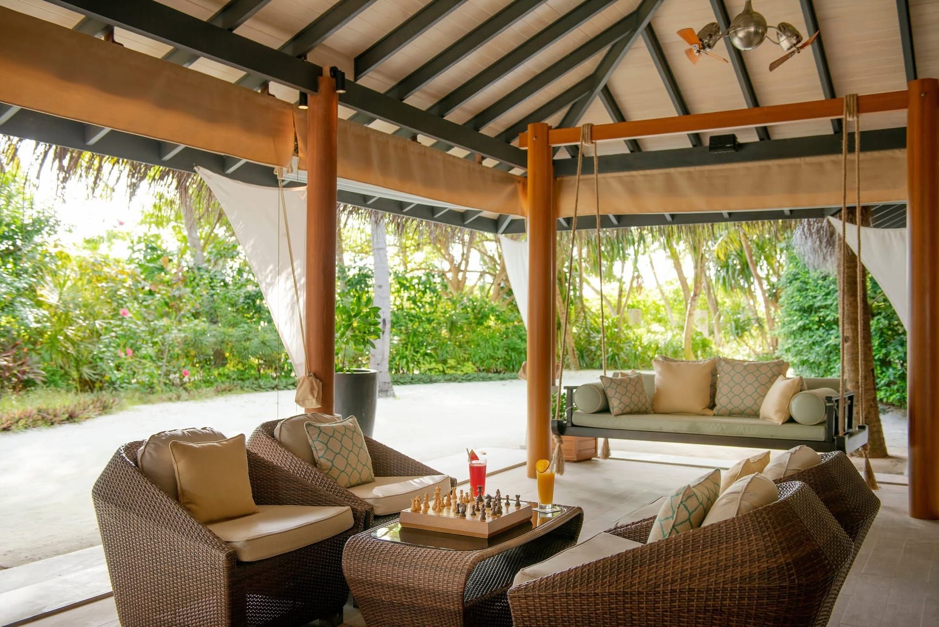 Open-air garden pavilion with rattan sofas and a hanging swing daybed
