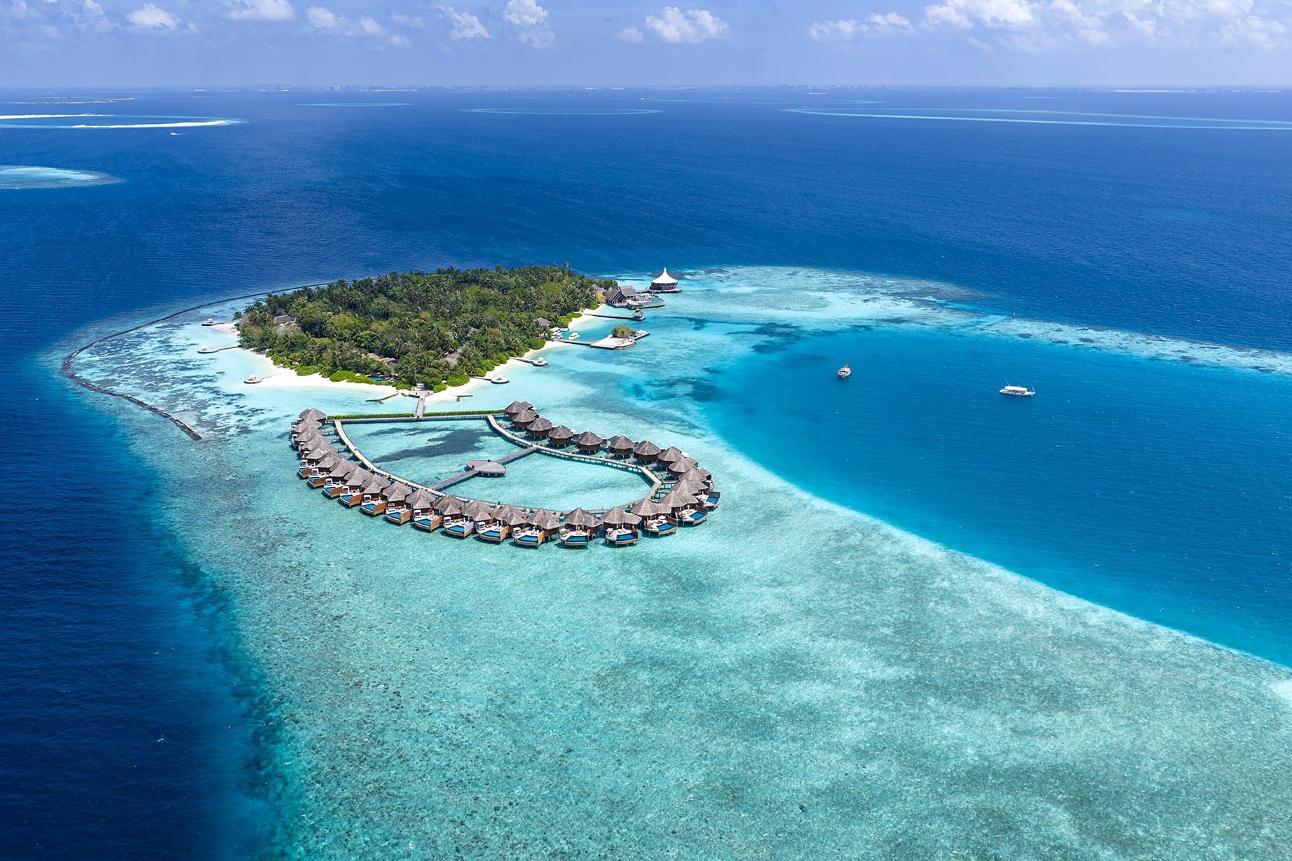 Aerial view of Baros island and its overwater villas surrounded by reef and ocean