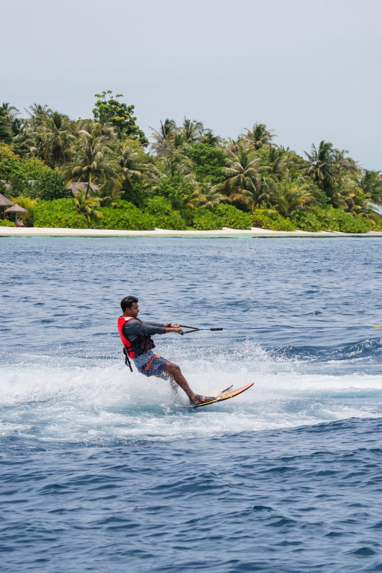 Man waterskiing across open water near a palm-fringed island