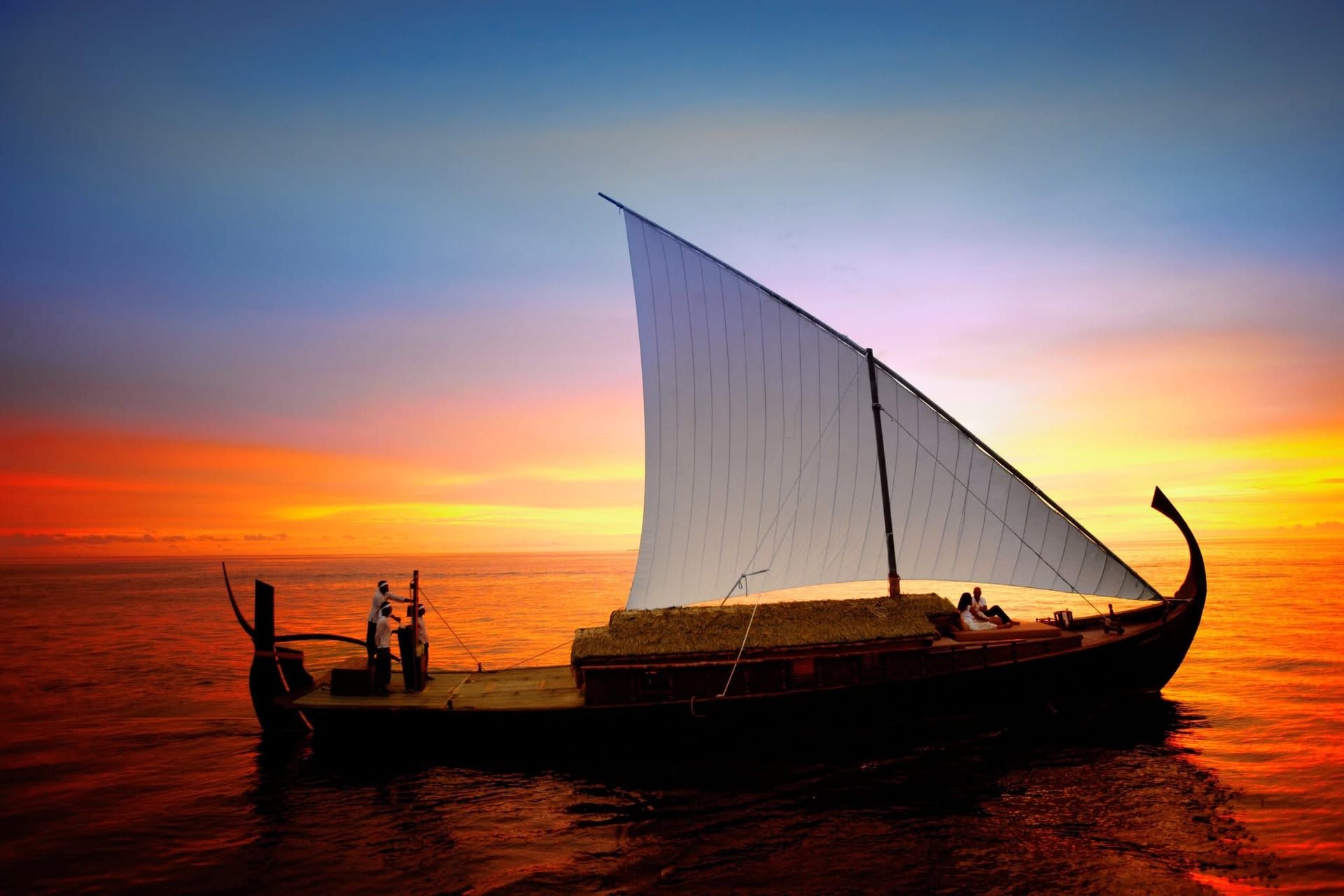 Silhouette of a dhoni under sail against a fiery sunset