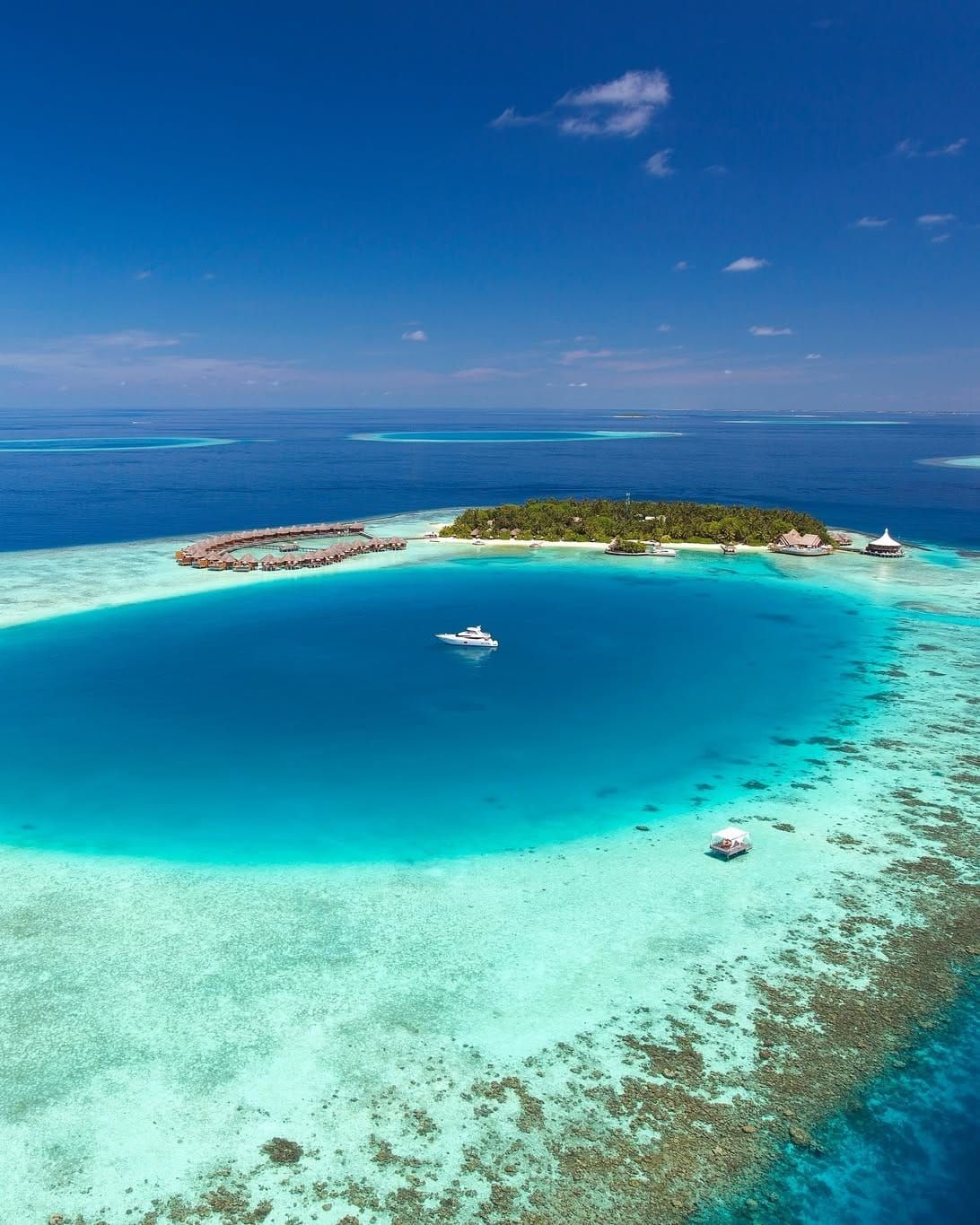 Aerial view of an island and a deep blue lagoon ringed by reef