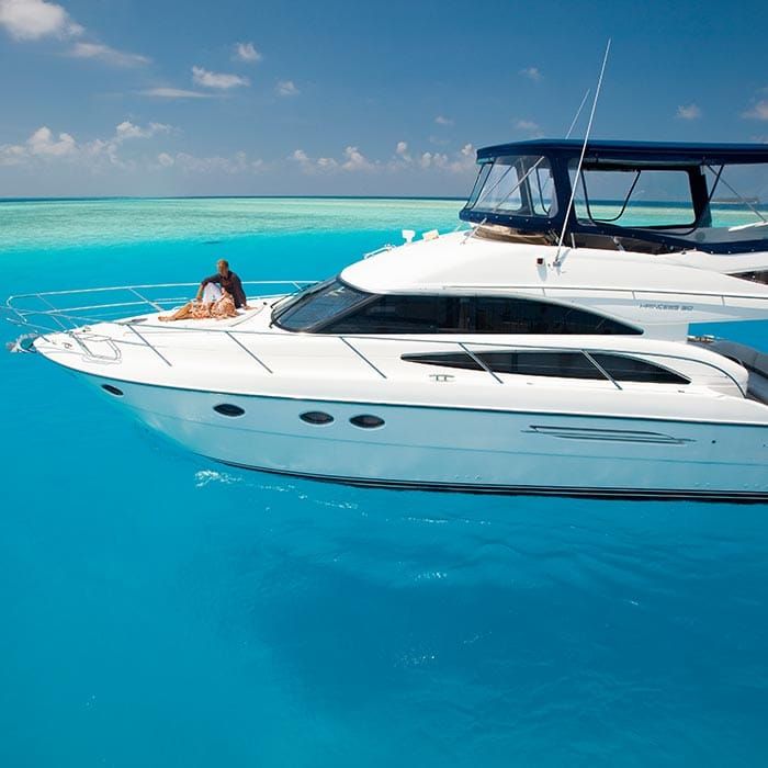 Woman relaxing on the bow of a white motor yacht in turquoise water