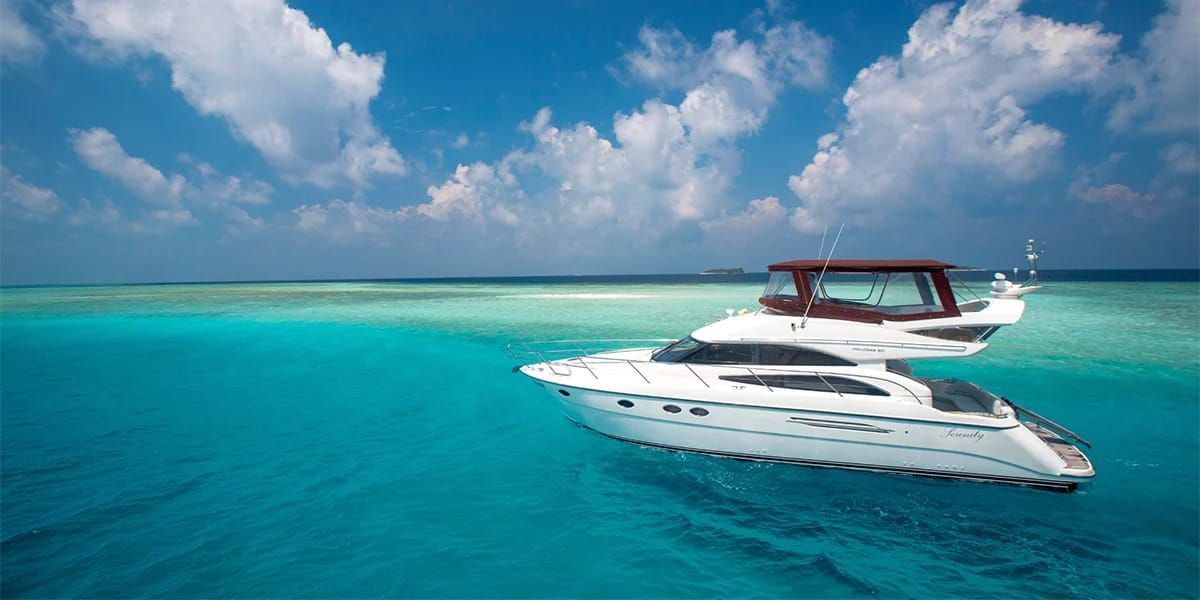 White motor yacht anchored in a turquoise lagoon under a blue sky