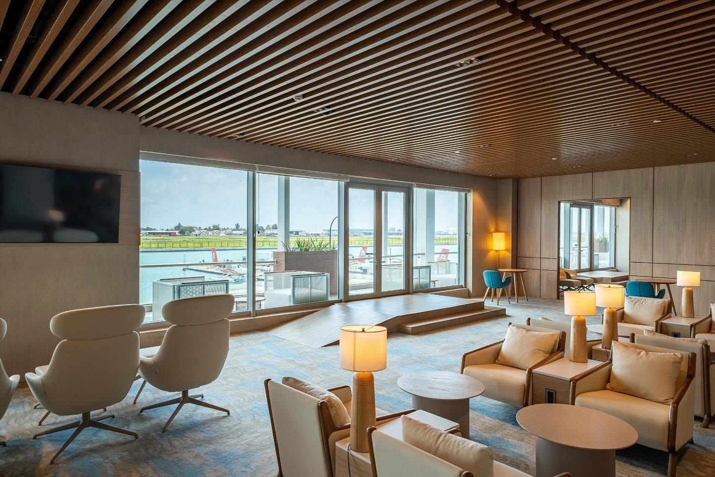 Airport lounge with armchairs, lamps and large windows onto the runway