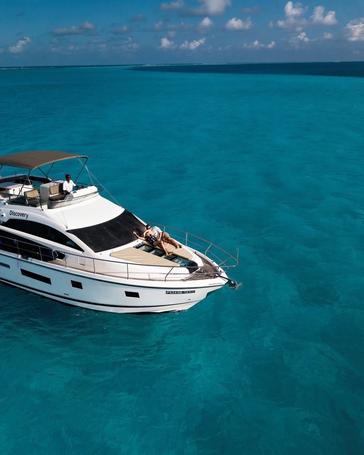 Aerial view of a white motor yacht in clear turquoise water