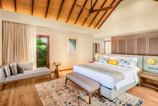Bright villa bedroom with a vaulted timber ceiling, rug and bench