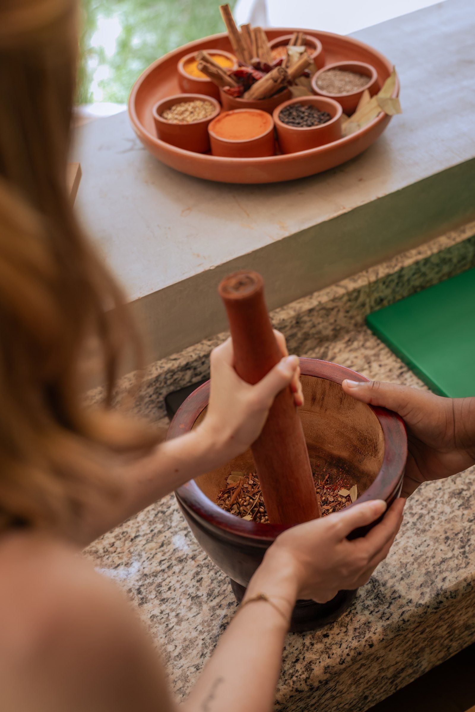 A guest grinding spices with a mortar and pestle at an Island Infusions session