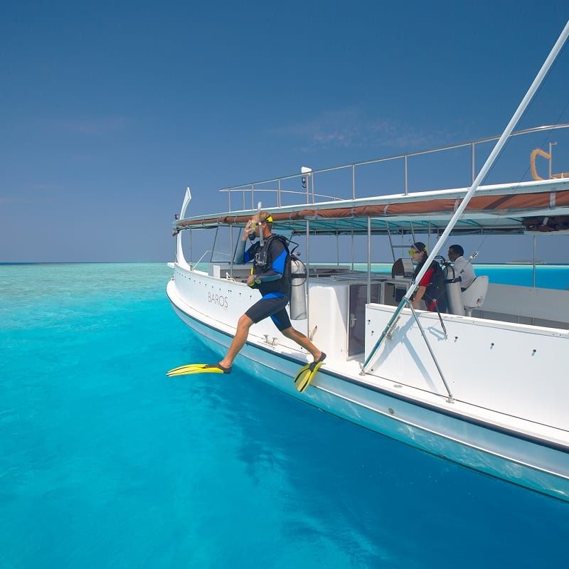 Diver jumping from a dive boat into clear turquoise water