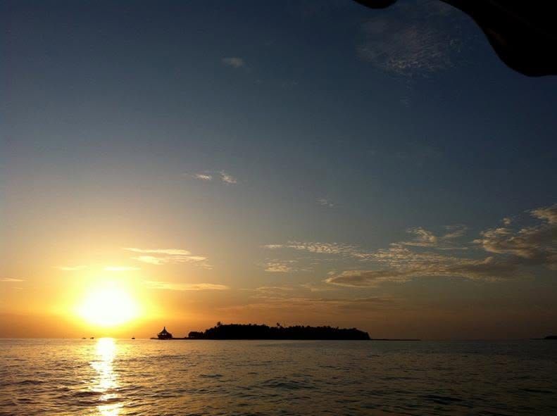 Sun setting over the sea with a distant island silhouette
