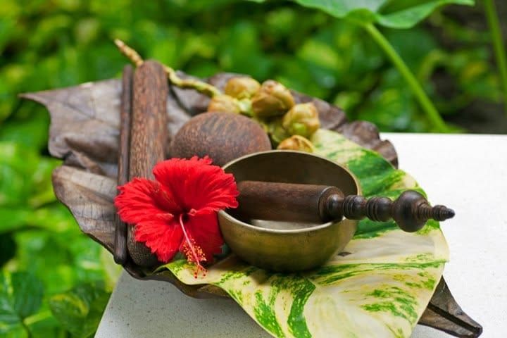 Tropical flowers, spices and a singing bowl arranged on a leaf