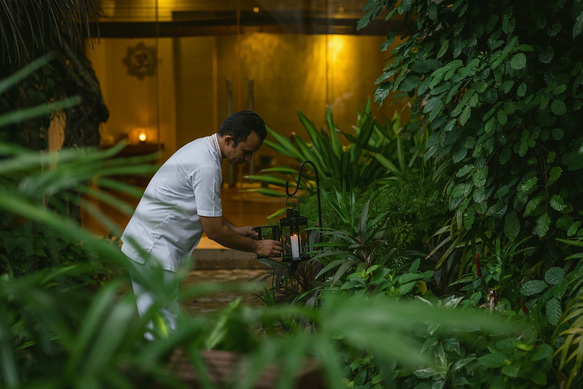 Therapist preparing a treatment amid jungle foliage outside a lit spa pavilion