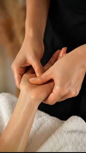 Close-up of hands massaging a guest's hand on a white towel
